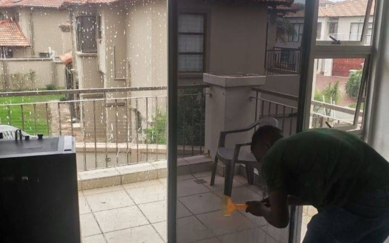 Technician applying tint film to a sliding door overlooking a townhouse complex