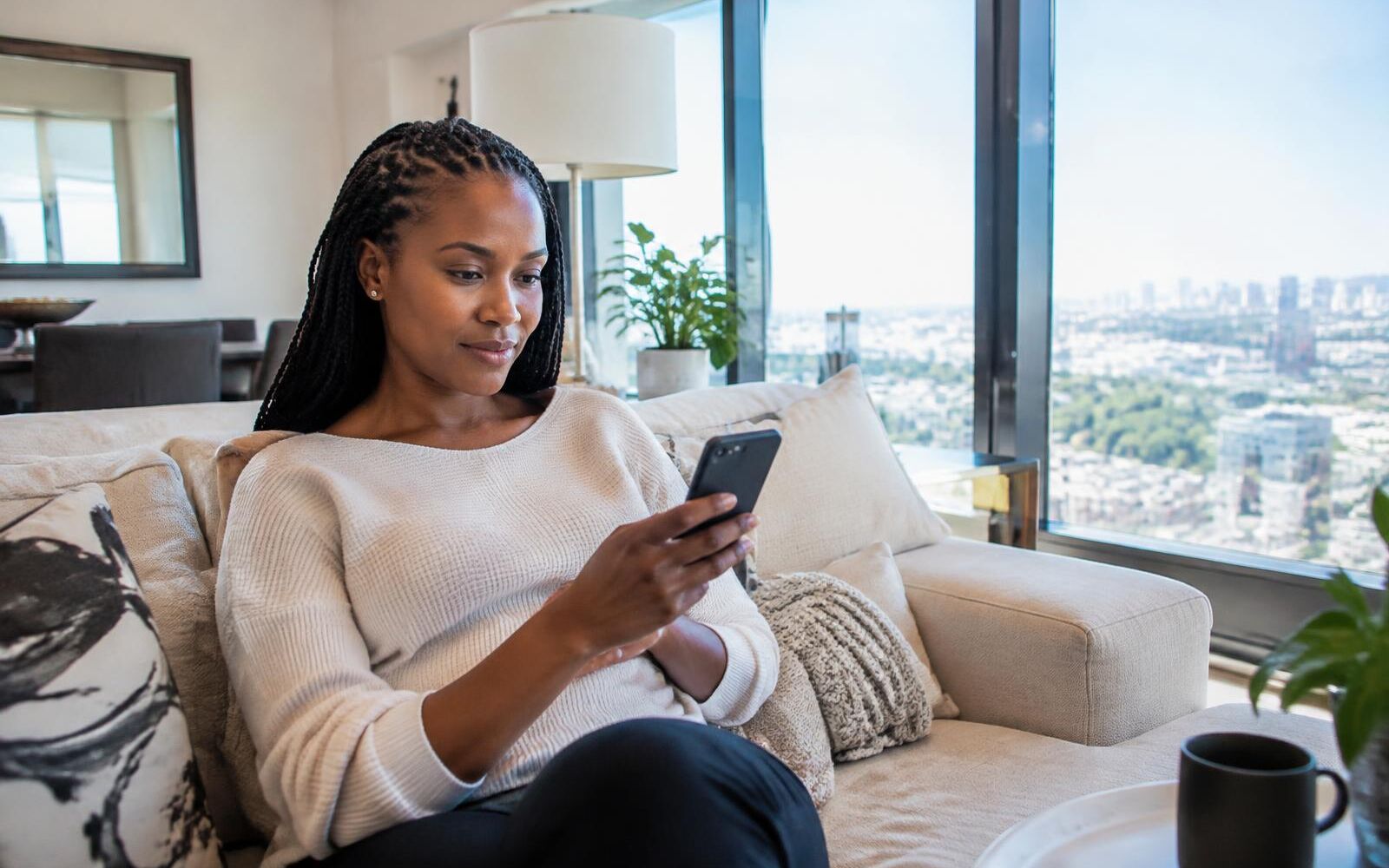 Woman on her phone in a bright living room with clean windows