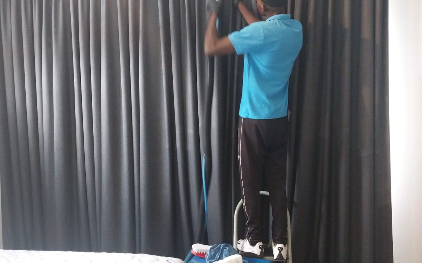 Team member cleaning bedroom curtains