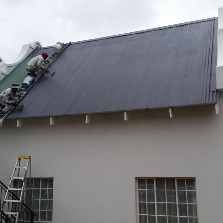 Team painting a roof on a double-storey home